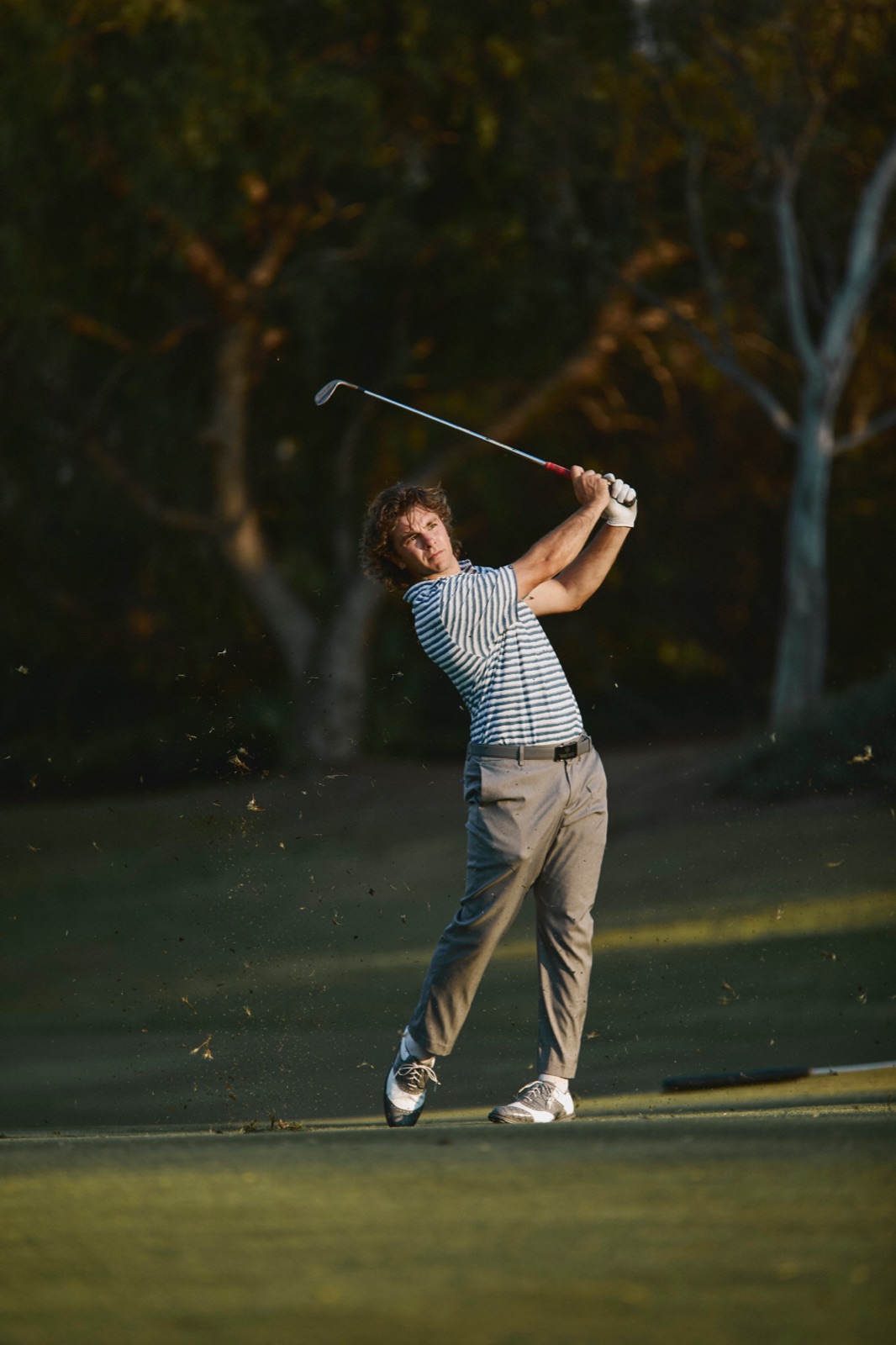 Ari mid follow-through on the fairway at sunset