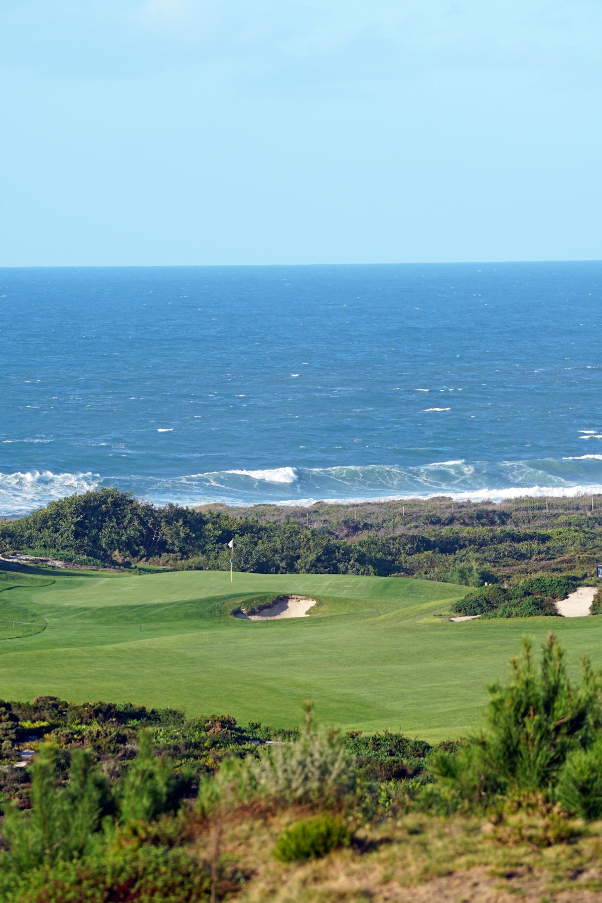 A green perched above the ocean, flag bending in the sea breeze